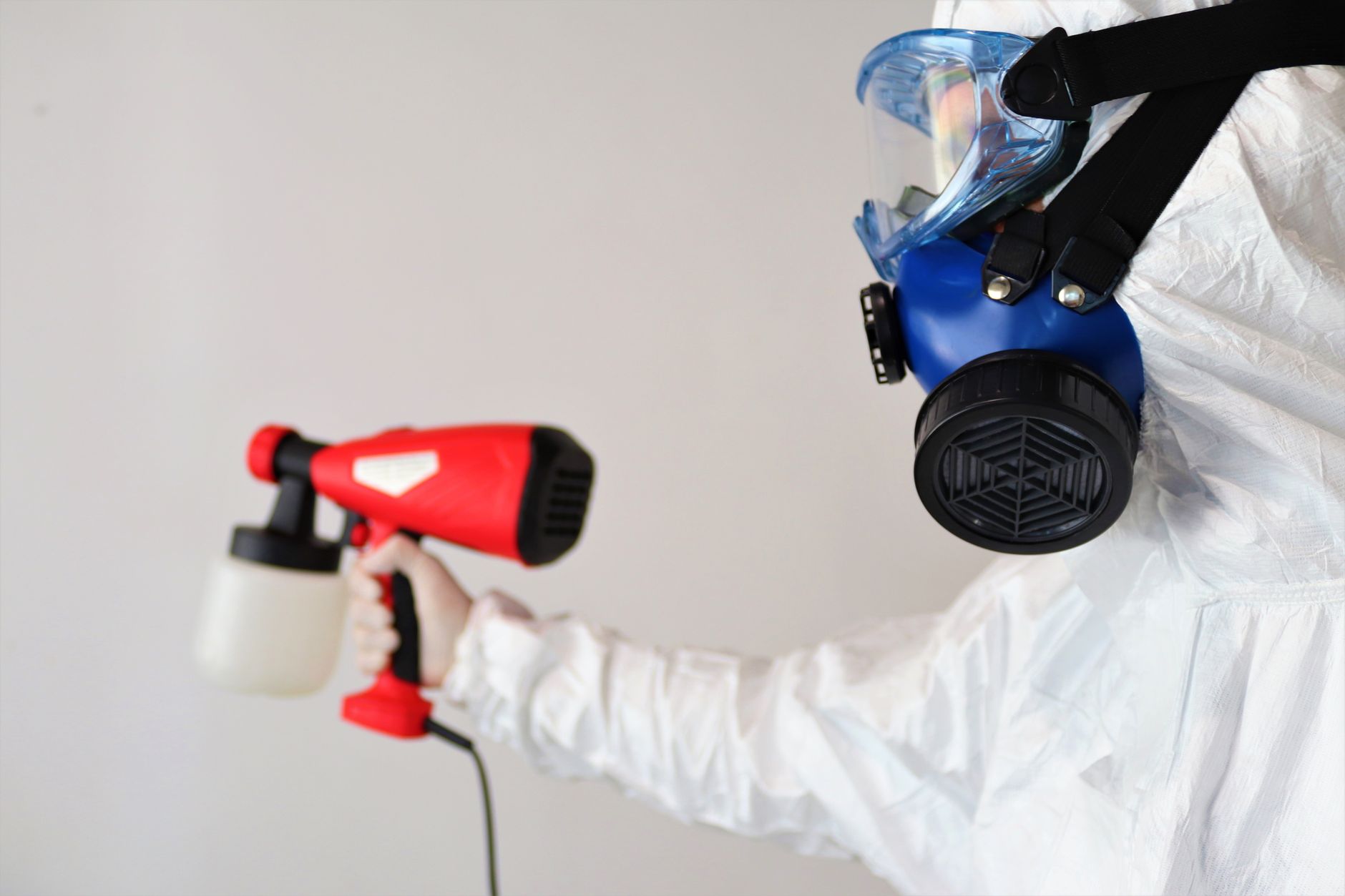 A certified mold remediation technician in full PPE inspecting a ceiling in a Prosper home, using a moisture meter to detect hidden moisture.